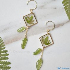 the earrings are made with green leaves and gold plated metal hooks, hanging from long earwires