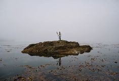 a person standing on top of a rock in the middle of a body of water