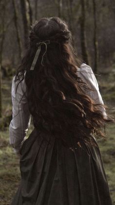 a woman with long hair walking in the woods