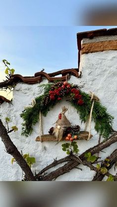 a wreath on the side of a building with decorations hanging from it's sides