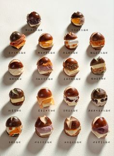 an assortment of donuts with different toppings arranged in rows on a white surface