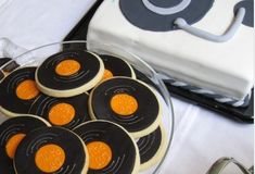 cookies are arranged in the shape of circles on a plate next to a white cake with black and orange icing