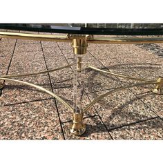 a glass and brass coffee table on top of a tile floor with gold trimmings