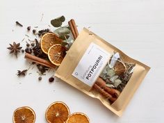 an image of dried orange slices and cinnamons on a white table with spices in the bag