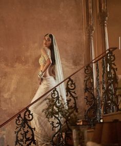 a woman in a white dress is standing on some stairs with her veil pulled back