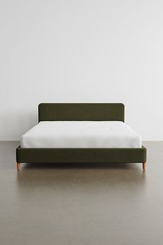 a bed sitting on top of a wooden floor next to a white wall