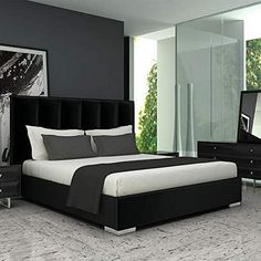 a black and white bedroom with a large bed in the middle, dressers and mirror on the wall