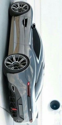 a grey sports car parked on the side of a wall next to a cup holder