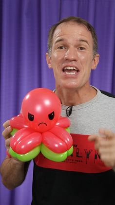 a man holding an inflatable octopus balloon and pointing to it's face