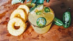 a pineapple margarita with sliced green peppers on the rim and garnishes