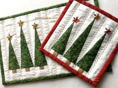 two quilted christmas tree placemats sitting on top of each other with red and green trim