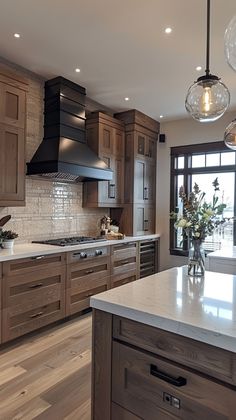 a large kitchen with wooden cabinets and marble counter tops, along with two pendant lights hanging from the ceiling