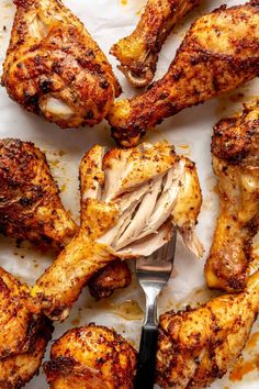 grilled chicken wings on a sheet of parchment paper with a fork in the middle