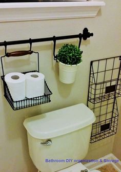 a white toilet sitting under a window next to a metal rack with two rolls of toilet paper