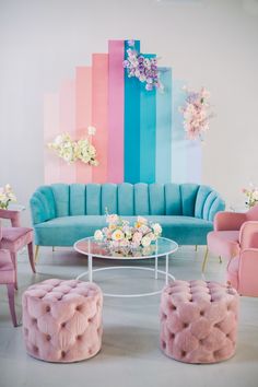 a living room filled with furniture and flowers on top of it's tables in front of a rainbow colored wall