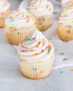 several cupcakes with white frosting and sprinkles