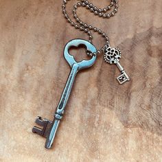 an old key is laying on top of a wooden table next to a ball chain