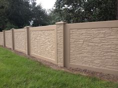 a brick fence with grass and trees in the backround, along side it