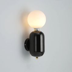 a black wall light with a white ball on it