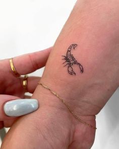 a woman's wrist with a small scorpion tattoo on the left side of her arm