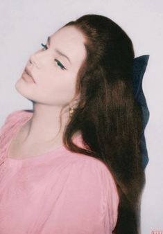 a woman with long brown hair wearing a pink shirt