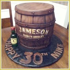 a birthday cake made to look like a barrel with the number 30 on it and two bottles next to it