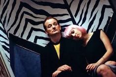 a man sitting next to a woman in front of a zebra print wall