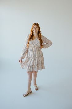 This beautiful neutral midi-length dress has all of the boho vibes! It is going to be your new go-to for date nights, weddings, and work events. This dress features a modest, shorter v-neckline and fluttery blouson long-sleeves. The blousy material flows beautifully down the dress's skirt, with the bottom featuring a tiered effect edged by ruffles. The smocked waist gives the dress an a-line fit that will accentuate your curves beautifully and provide structure to this extra flowy dress. The lin Spring Boho Knee-length Dress With Boho Print, Spring Knee-length Boho Dress, Spring Boho Print Midi Dress, Spring Boho Midi Dress For Garden Party, Spring Garden Party Boho Midi Dress, Spring Beige Boho Dress With Boho Print, Spring Beige Boho Print Dress, Beige Boho Print Dress For Spring, Beige Boho Dress With Print For Spring