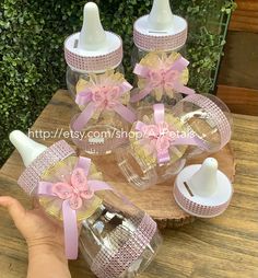 the baby bottles have pink bows and are sitting on top of a wooden table with other items