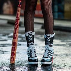 the legs and shoes of a woman holding a baseball bat