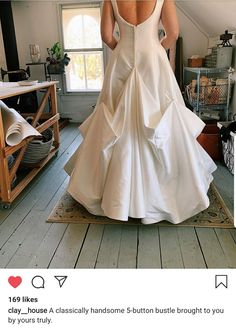 a woman in a white wedding dress is standing on a rug with her back to the camera