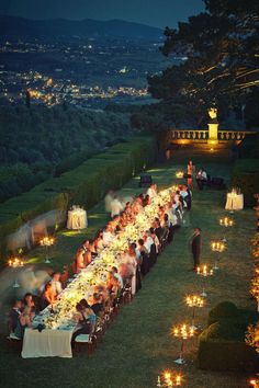 a long table is set with candles and people are sitting at the tables in front of them