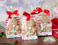 three gingerbread cookies wrapped in cellophane and tied with red ribbon, sitting on a table