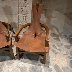 two wooden chairs sitting next to each other on a stone floor