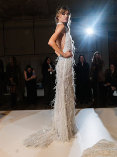 a woman in a white dress standing on a runway