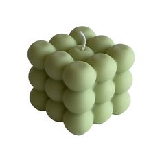 a bunch of green balls sitting in the middle of a white background with an apple on top