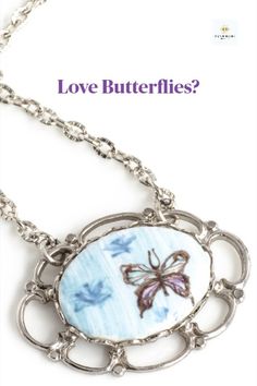 Vintage porcelain cameo in oval shape with a light blue background, small light blue butterflies, and one large purple butterfly in a silver scalloped pendant, finished with a an etched silver plated chain.