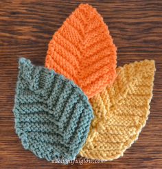 three knitted hats sitting on top of a wooden table