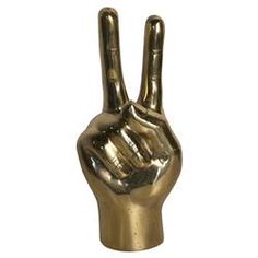 a gold colored metal peace sign with one hand raised in the air, against a white background