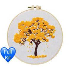 an embroidered tree with yellow leaves is shown in front of a white background and blue heart