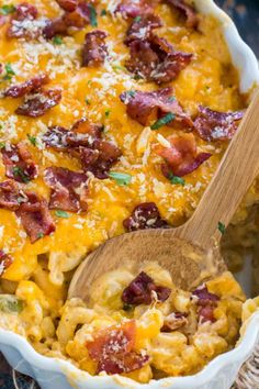 a casserole dish with bacon, cheese and bread in it next to a wooden spoon