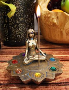 a candle holder with a woman sitting on top of it and seven chakras