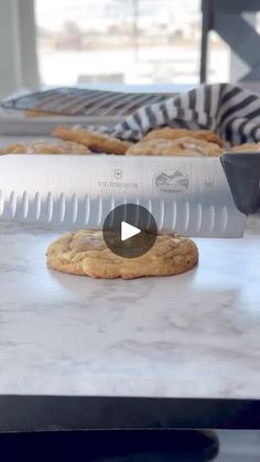 a cookie being cut into pieces with a large knife on the counter top next to it