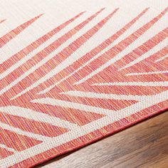 an orange and white area rug on top of a wooden floor next to a wood table