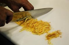 a person is cutting up some food on a white counter top with a large knife