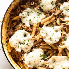 a pot filled with pasta and sauce covered in cheese on top of a marble counter