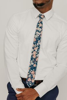 We pride ourselves in offering our customers some of the best skinny ties money can buy. Each DAZI tie is handmade from high quality imported fabrics. Features: Approx. 2.5" wide at the tip Approx. 58" in length 100% Cotton Background color: Navy. In some pictures it may appear faded black, but it is navy. Don't forget a matching pocket square! Shop our ﻿Lotus Pocket Square. Dapper Fitted Tie, Dapper Fitted Standard Tie, Dapper Standard Tie, Semi-formal Summer Standard Tie, Fitted Cotton Tie, Fitted Neckwear For Black Tie Spring Events, Fitted Cotton Neckwear For Business, Fitted Cotton Suit And Tie Accessories, Spring Black Tie Event Ties