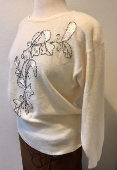 "White Lambswool Angora Pullover Sweater with Beaded Embroidered Leaf Design, by Renee Tener for Jeanne Pierre Size Medium This sweater is almost perfect except for 1 small mend job (pic no. 8) Features are a 3\" sock bottom along with end of sleeves, shoulder pads that can be removed and a beautiful beaded embroidered design on the front. The tube beads look like a dark silver and they edge the design that is filled with shimmery white embroidery stitches and also silver stud like beads. Really Elegant Embroidered Winter Sweater, Elegant White Embroidered Sweater, Embroidered Wool Sweater For Fall, Fall Embellished White Tops, Winter Cream Embroidered Sweater, Cream Embroidered Sweater For Winter, Elegant Embroidered Winter Tops, Elegant Floral Embroidered Tops For Winter, Winter Cream Tops With Floral Embroidery