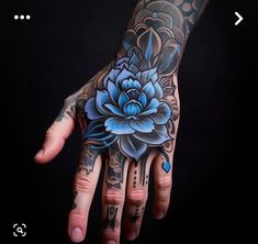 a person's hand with a blue flower tattoo on it and an arrow in the middle