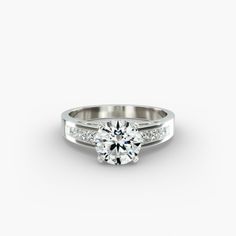 a white gold engagement ring with channel set diamonds on the sides and a round center stone